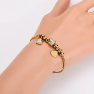 Nahaufnahme eines 18k vergoldeten Schlangenarmbands mit Herzanhängern für Damen