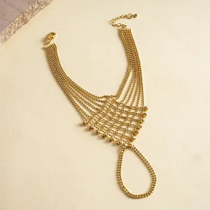 Close-up view of an intricate gold-toned multi-strand bead chain slave bracelet hand harness.