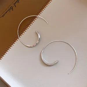 Nahaufnahme von minimalistischen silbernen Creolen mit poliertem Finish auf Leder