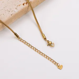 Detail eines goldenen Edelstahl-Schlangenarmbandes mit Herzanhänger und Karabinerverschluss