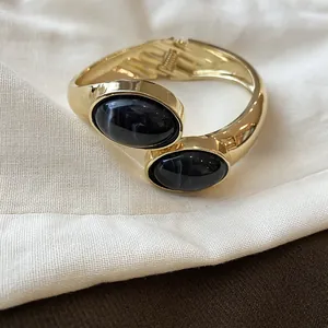 Dettaglio del bracciale rigido dorato con pietre in resina nera marmorizzata
