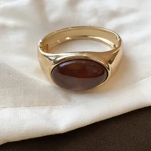 Dettaglio di un bracciale dorato vintage con un inserto ovale in resina ambra