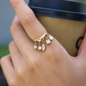 Detailaufnahme eines goldenen Wellenrings aus Edelstahl mit fünf hängenden Zirkonia-Steinen