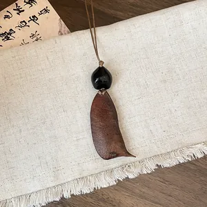 Close-up of a rustic wooden geometric pendant on a textured linen background.