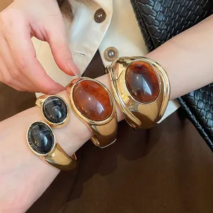 Primo piano di bracciali aperti dorati con resina ovale color ambra e nera