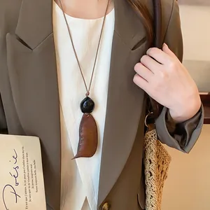 Close-up of New Chinese style retro wood pendant necklace worn with brown blazer