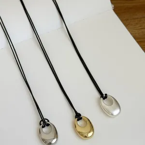 Minimalist oval pendant necklaces on black cord in gold and silver finishes