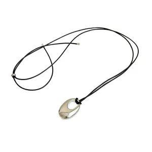 Minimalist silver oval pendant necklace with adjustable black leather cord cord.