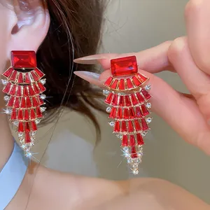 Detailed view of fan-shaped red rhinestone tassel earrings with elegant golden finish
