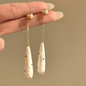 Detail view of vintage French style water drop pearl earrings with brown polka dots.