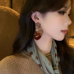 Close-up view of Maillard style resin heart earrings with wooden and woven details