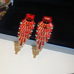 Detailed macro shot of elegant fan-shaped red crystal earrings with gold trim.