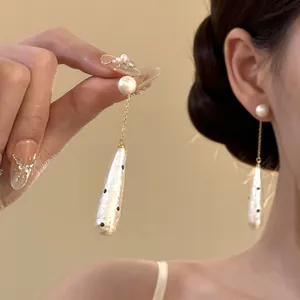 Detail view of vintage polka dot pearl drop earrings worn by a model