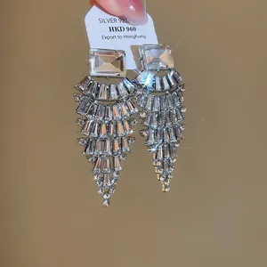 Detail view of sparkling silver-tone fan-shaped dangle earrings with clear crystals.