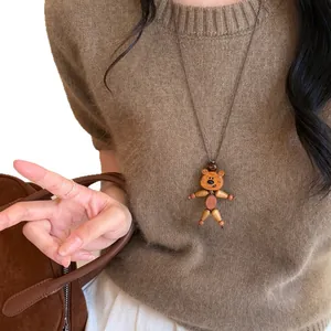 Handgefertigte Holzbär-Halskette mit Lederband über einem braunen Pullover getragen