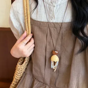 Nahaufnahme einer handgefertigten Holzbären-Halskette mit Perlenquasten an einem Model