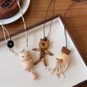 Detail handgefertigter Tieranhänger aus Holz mit Lederkordeln und Muschelperlen für Ketten