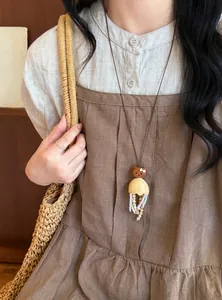 Detailansicht einer süßen Katzen-Halskette aus Holz, getragen über einem braunen Kleid.