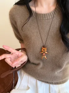 Nahaufnahme einer süßen Bärenhalskette aus Holz mit Lederband auf einem braunen Pullover.