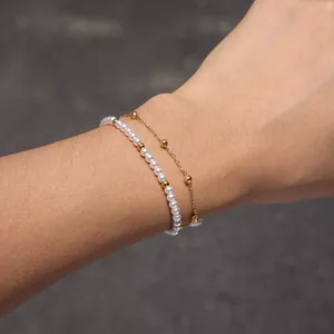 Vue rapprochée d'un élégant bracelet double épaisseur en perles et billes dorées au poignet