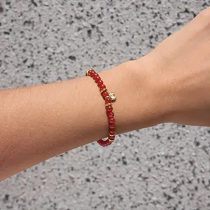 Détail d'un bracelet en perles d'agate rouge avec des accents plaqués or et zircon