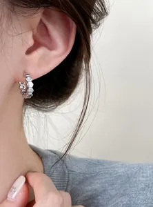 Close-up of hexagonal zircon hoop earring with 18k gold plating on an ear.
