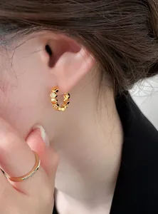 Detailed view of 18k gold plated hexagonal hoop earrings with zircon on model's ear