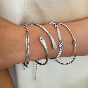 Primo piano di un set di 4 braccialetti d'argento con perle e occhio della fortuna al polso