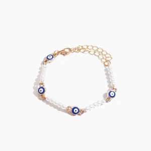 Elegante bracciale di perle con ciondoli a occhio blu e catena regolabile dorata.