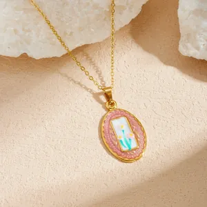 Detailed macro view of an elegant gold-plated enamel oval pendant with floral motifs