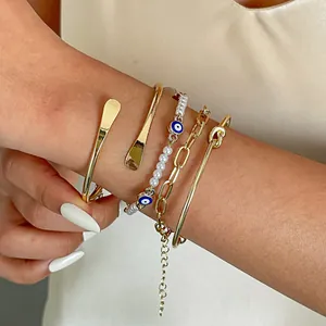 Vista dettagliata del set di 4 gioielli con polsini dorati e braccialetto di perle Evil Eye