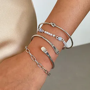 Dettaglio ravvicinato del set di 4 bracciali in metallo con perle e occhio greco
