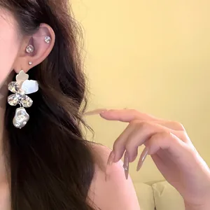 Dettaglio di orecchini a fiore bianco stile francese con strass e perle sull'orecchio