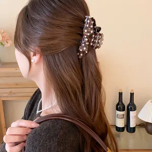 Detail shot of an elegant Korean retro brown polka dot bow hair claw clip in a bun.