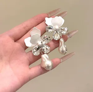 Vista dettagliata degli orecchini a fiore bianco con strass e perle barocche eleganti