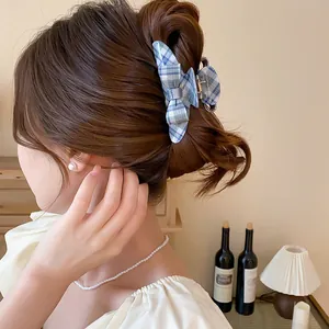 Detail view of a vintage blue plaid bow hair claw clip styled in a woman's updo.