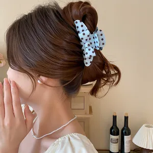 Detailed view of a stylish blue polka dot bow hair claw clip styled on a model's hair bun