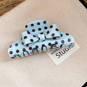 Detail view of a light blue retro polka dot bow hair claw clip for women's styling.