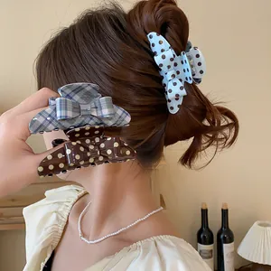 Detail of retro polka dot and plaid bow hair claw clips on a messy bun hairstyle