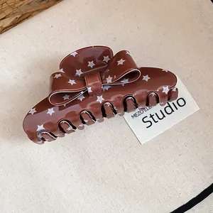 Detailed macro shot of a brown retro bow hair claw clip with white star patterns