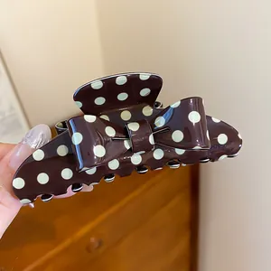 Detailed macro view of retro brown hair claw clip with cream polka dots and bow