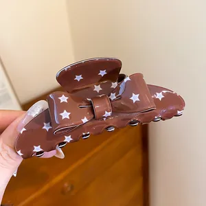 Close-up of brown bow hair claw clip with white star pattern for elegant hair styling