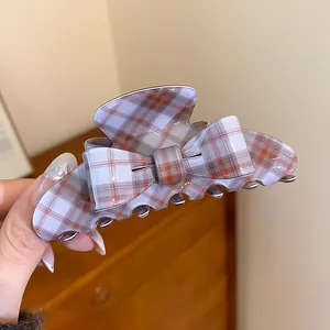 Detailed view of a plaid pattern bow hair claw clip for elegant hair styling and updos.