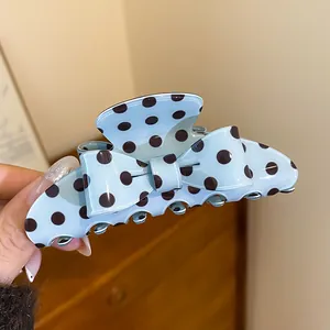 Close-up detail of a light blue polka dot bow hair claw clip for elegant hair styling
