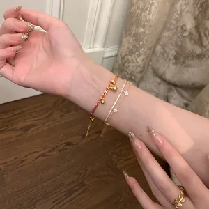 Vue détaillée de bracelets superposés en plaqué or 24K avec zircons et trèfles