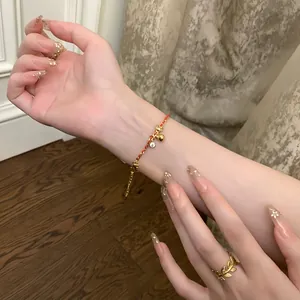 Gros plan d'un élégant bracelet en zircon plaqué or 24K et d'une bague feuille à la main.