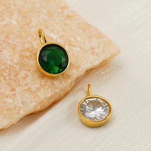 Detailed view of round emerald and clear zircon pendants with gold stainless steel frames