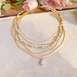 Detailansicht einer mehrlagigen Goldkette mit Perlen und einem Barockperlenanhänger.