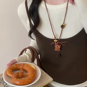 Detailed close-up of a cute wooden bear pendant necklace worn over a brown camisole.