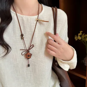 Detail shot of a cute handmade wooden puppy pendant necklace on a cream sweater